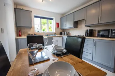 a kitchen with a wooden table with wine glasses on it at Brook - Sizewell - Contractor Accommodation in Saxmundham