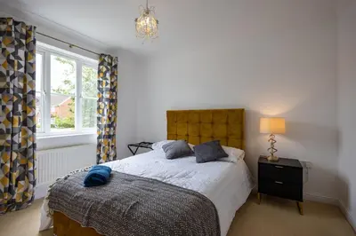 a bedroom with a bed and a lamp and a window at Brook - Sizewell - Contractor Accommodation in Saxmundham
