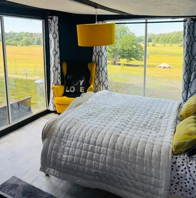 a bedroom with a large bed and a large window at Lookout cabin farm stay firepit Hertford in Hertford