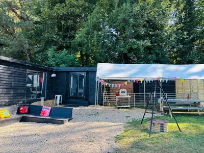 a tent in front of a cabin with a picnic table at Lookout cabin farm stay firepit Hertford in Hertford