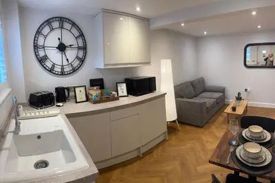 a kitchen and living room with a clock on the wall at Little Dunton Lodges 1 in Little Burstead