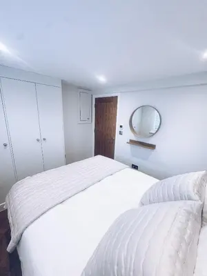 a white bedroom with a large bed and a mirror at Little Dunton Lodges 1 in Little Burstead