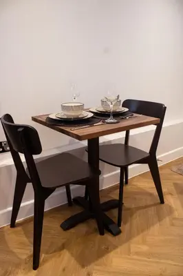 a wooden table and chairs with plates and glasses on it at Little Dunton Lodges 1 in Little Burstead