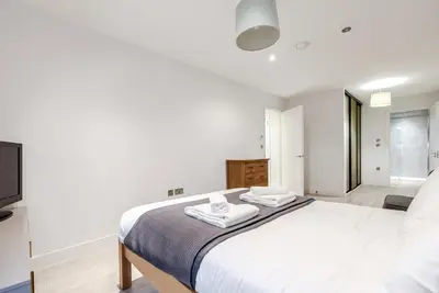 a white bedroom with a bed and a television at Tailored Stays - Central Station Apartments in Cambridge