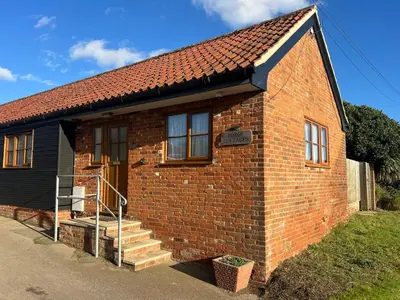 a small brick house with a staircase leading to the door at Charming 1BR Cottage in Aldringham in Aldringham