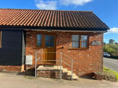 a small brick house with a brown door and stairs at Charming 1BR Cottage in Aldringham in Aldringham