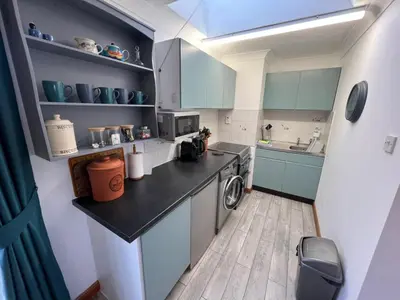 a small kitchen with blue cabinets and a washing machine at Charming 1BR Cottage in Aldringham in Aldringham
