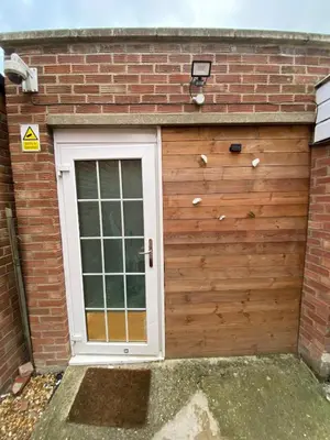 a garage with a door and a brick building at Charming Cambridge Studio with Private Garden in Cherry Hinton