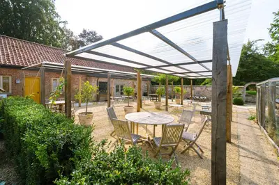 a patio with a table and chairs under a pergola at Chippenham Park Garden Rooms in Chippenham