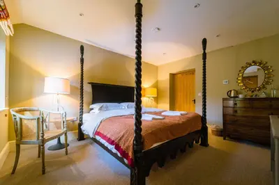 a bedroom with a four poster bed and a chair at Chippenham Park Garden Rooms in Chippenham