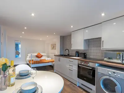 a kitchen with white cabinets and a table with dishes on it at Pass the Keys Cosy Studio in Basildon Sleeps up to 4 in Basildon