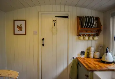 a kitchen with a door and a counter with a counter top at Shepherd Hut in the woods