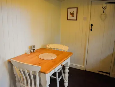 a dining room table with two chairs and a door at Shepherd Hut in the woods