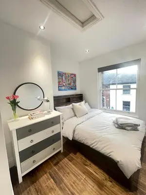 a bedroom with two beds and a dresser with a mirror at Perfectly located and cozy flat in Bury Saint Edmunds