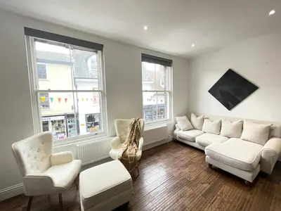 a living room with white furniture and windows at Perfectly located and cozy flat in Bury Saint Edmunds