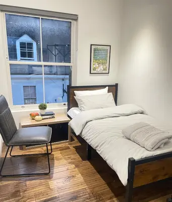 a bedroom with two beds and a chair and a window at Perfectly located and cozy flat in Bury Saint Edmunds