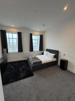 a bedroom with a bed and a couch and windows at Cosy one bedroom flat in the heart of Chelmsford in Chelmsford