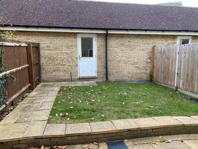 a backyard with a yard with a door and a fence at Warm & Cosy 4 Bed Cambridge House w Parking Garden & High Speed WIFI in Milton