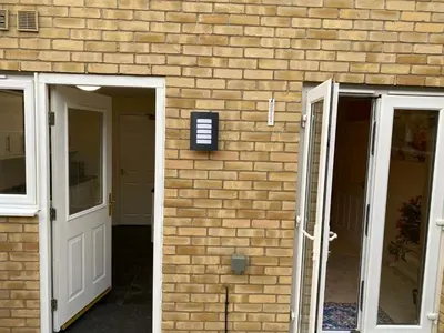 a brick building with two doors and a brick wall at Warm & Cosy 4 Bed Cambridge House w Parking Garden & High Speed WIFI in Milton