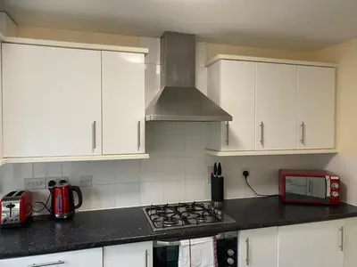 a kitchen with white cabinets and a stove top oven at Warm & Cosy 4 Bed Cambridge House w Parking Garden & High Speed WIFI in Milton