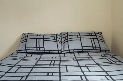 a bed with black and white sheets and pillows at Serene 5BR - A Cozy Home Away From Home in Theydon Bois