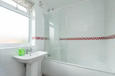 a white bathroom with a sink and a shower at Serene 5BR - A Cozy Home Away From Home in Theydon Bois
