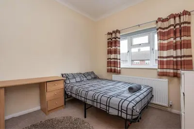 a bedroom with a bed and a desk and a window at Serene 5BR - A Cozy Home Away From Home in Theydon Bois