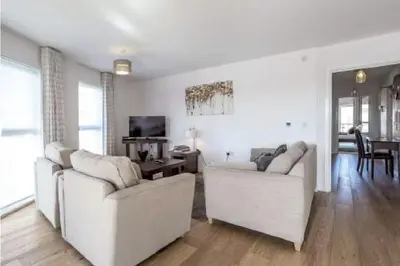 a living room with two white couches and a television at The Luxurious Semi-Circle in Cambridge