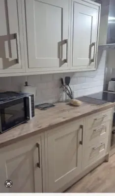 a kitchen with white cabinets and a microwave at 2 Bedroom Garden Flat in Halesworth