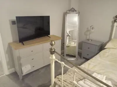 a bedroom with a television and a dresser with a mirror at 2 Bedroom Garden Flat in Halesworth