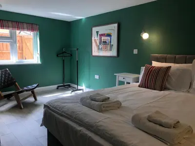 a bedroom with a large bed with green walls at Perfitt Place in Bungay