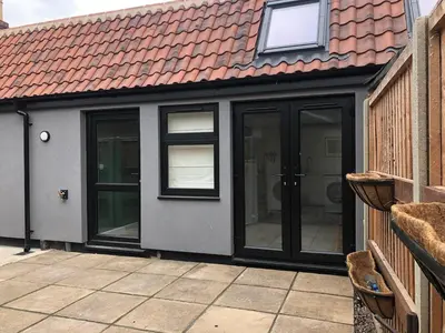 a house with glass doors and a red roof at Perfitt Place in Bungay