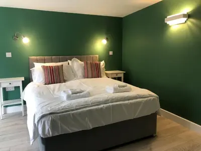 a bedroom with a large bed with green walls at Perfitt Place in Bungay