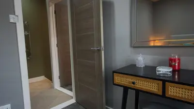 a bathroom with a wooden door and a table with a mirror at Colchester Luxury Apartments - Colonia in Colchester