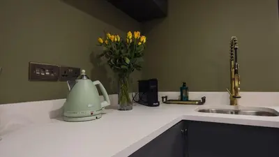 a kitchen counter with a sink and a vase with yellow flowers at Colchester Luxury Apartments - Colonia in Colchester