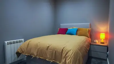 a bedroom with a bed with colorful pillows on it at Colchester Luxury Apartments - Colonia in Colchester