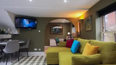 a living room with a green couch and a tv at Colchester Luxury Apartments - Colonia in Colchester