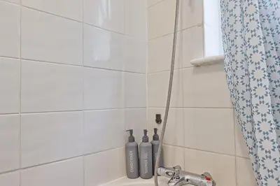 a bathroom with a shower with two bottles on the tub at Comfortable 2-Bedroom Home for 6, Perfect for Families, Contractors & Longer Stays, Clark Property Estates in Southend-on-Sea