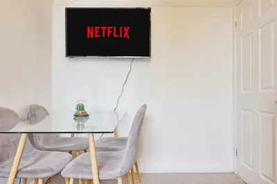 a table and chairs with anetflix sign on the wall at Comfortable 2-Bedroom Home for 6, Perfect for Families, Contractors & Longer Stays, Clark Property Estates in Southend-on-Sea