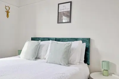 a bedroom with a white bed with a green headboard at Comfortable 2-Bedroom Home for 6, Perfect for Families, Contractors & Longer Stays, Clark Property Estates in Southend-on-Sea