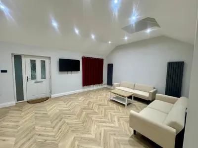 a living room with two couches and a flat screen tv at Richard guest house in Roydon