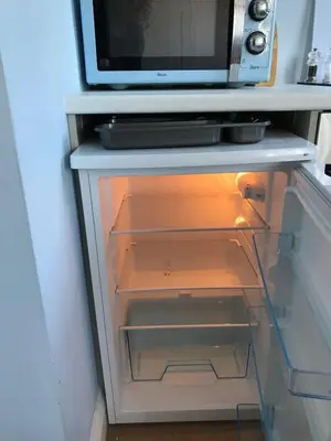 an empty refrigerator with a microwave on top of it at Stylish self contained city apartment in Milton