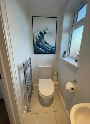 a bathroom with a toilet and a painting on the wall at Stylish self contained city apartment in Milton