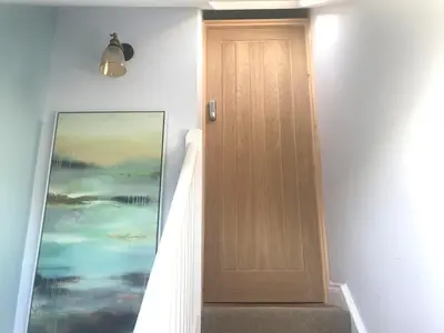 a wooden door in a hallway next to a painting at Stylish self contained city apartment in Milton