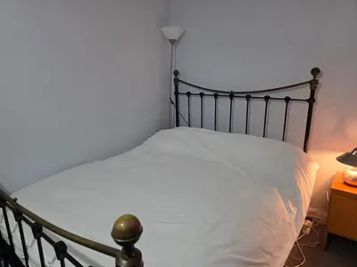 a bedroom with a bed with white sheets and a lamp at Guest Room in Colchester Hythe in Colchester