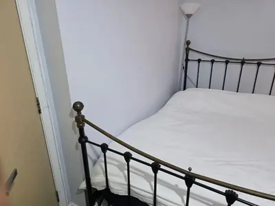 a bedroom with a bed with white sheets and a lamp at Guest Room in Colchester Hythe in Colchester