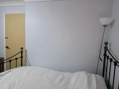 a bedroom with a bed with white sheets and a lamp at Guest Room in Colchester Hythe in Colchester