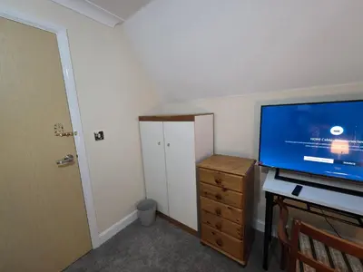 a room with a tv and a desk with a dresser at Charming Colchester Room with Garden Views in Colchester
