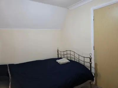 a bedroom with a bed with a blue blanket at Charming Colchester Room with Garden Views in Colchester