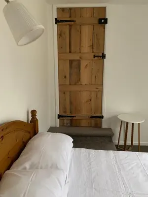 a bedroom with a bed and a wooden door at Bell Cottage in Mildenhall